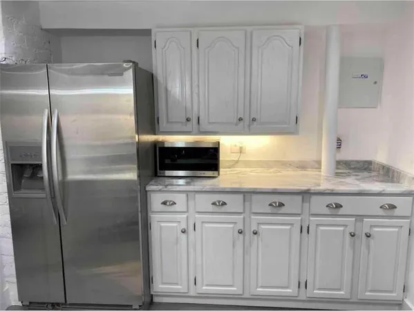 a kitchen with granite countertop a refrigerator and cabinets