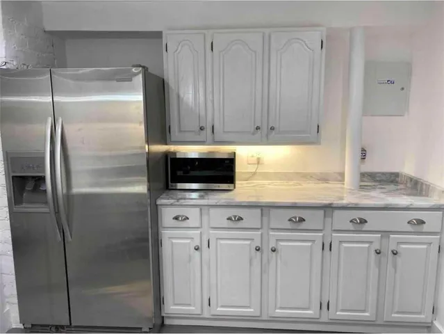 a kitchen with granite countertop a refrigerator and cabinets