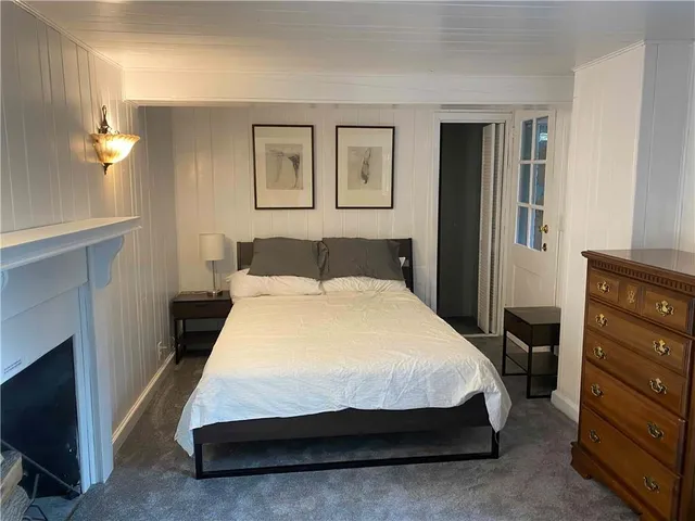 a spacious bedroom with a bed and a flat tv screen on dresser