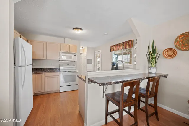 a kitchen with stainless steel appliances granite countertop a kitchen island a stove a refrigerator and a dining table with wooden floor