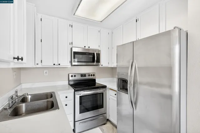a kitchen with granite countertop white cabinets and stainless steel appliances