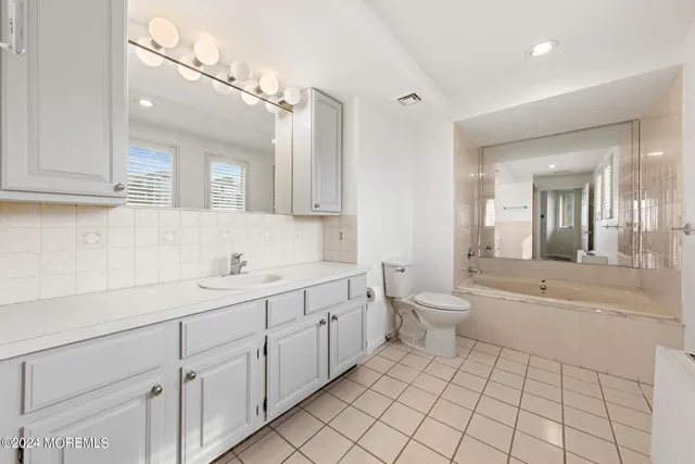 a spacious bathroom with a granite countertop sink a toilet and a bathtub