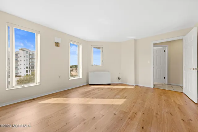 a view of an empty room with a window and wooden floor