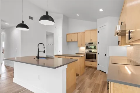 a kitchen with stainless steel appliances granite countertop a sink a stove a refrigerator and island with wooden floor