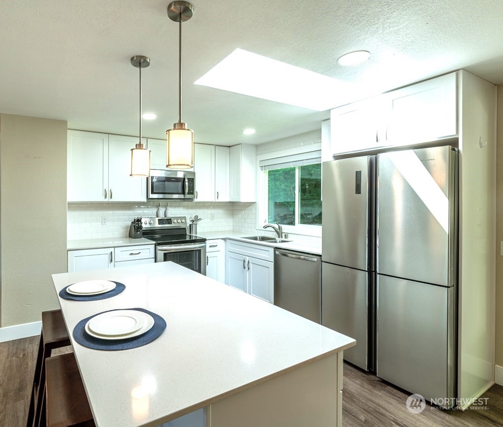1301 234th Street Southwest Bothell, WA 98021 - Photo 5 of 21 a kitchen with stainless steel appliances a refrigerator a stove a sink and a chandelier
