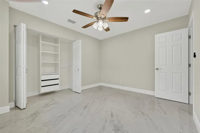 an empty room with closet and fan