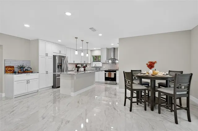 a kitchen with stainless steel appliances a table and chairs in it