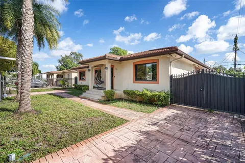 a front view of a house with a yard and potted plants