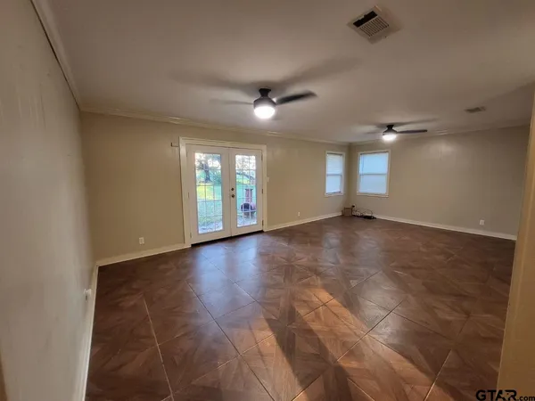 an empty room with wooden floor and windows