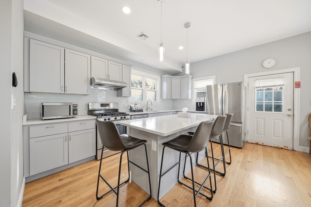 5 Main Street Quincy, MA 02169 - Photo 12 of 42 a kitchen with stainless steel appliances granite countertop a stove a sink dishwasher and a refrigerator with wooden floor