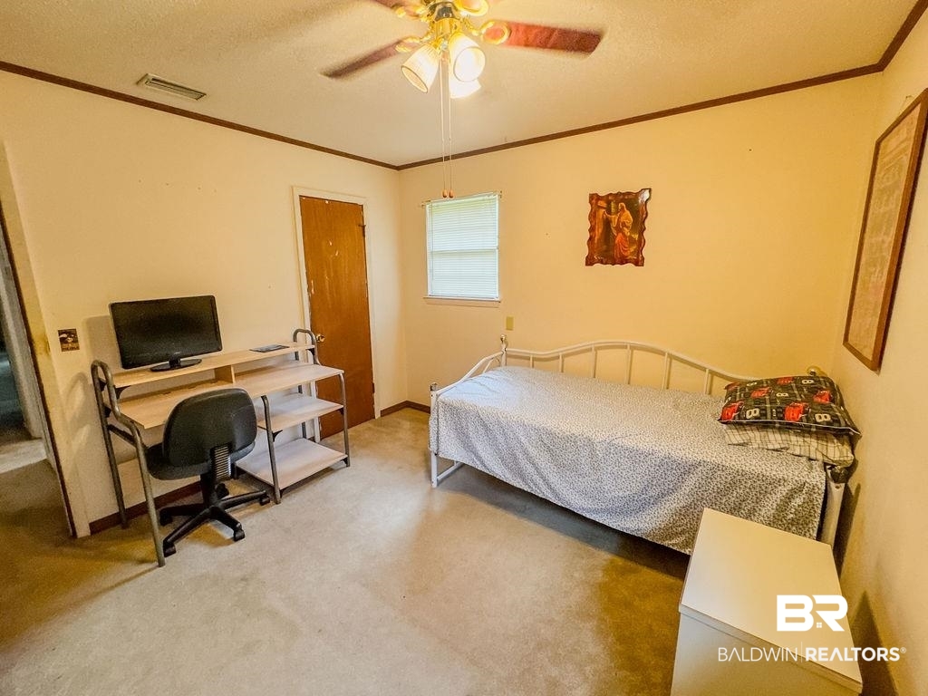 1456 Allen Walker Road Grove Hill, AL 36451 - Photo 22 of 28 Bedroom featuring a textured ceiling, ornamental molding, an office area, ceiling fan, and carpet floors
