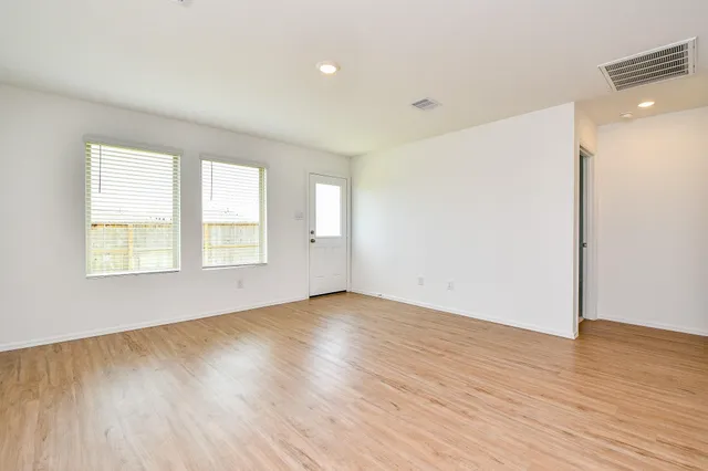 an empty room with wooden floor and windows