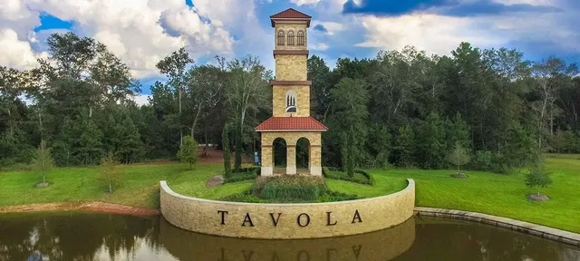 a view of a white house with a yard potted plants and large trees