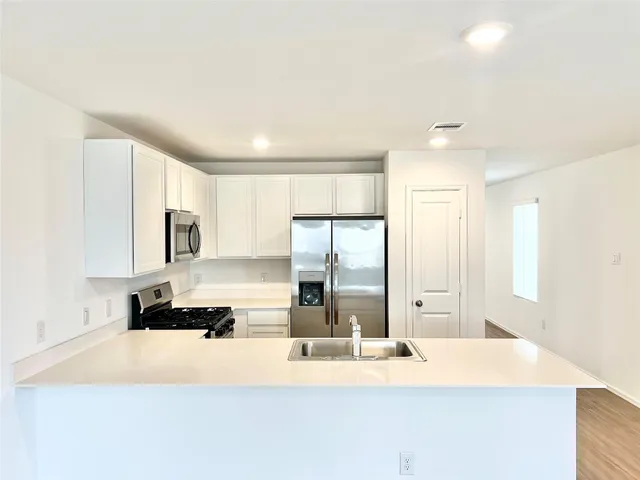 a kitchen with kitchen island a counter top space a sink and cabinets