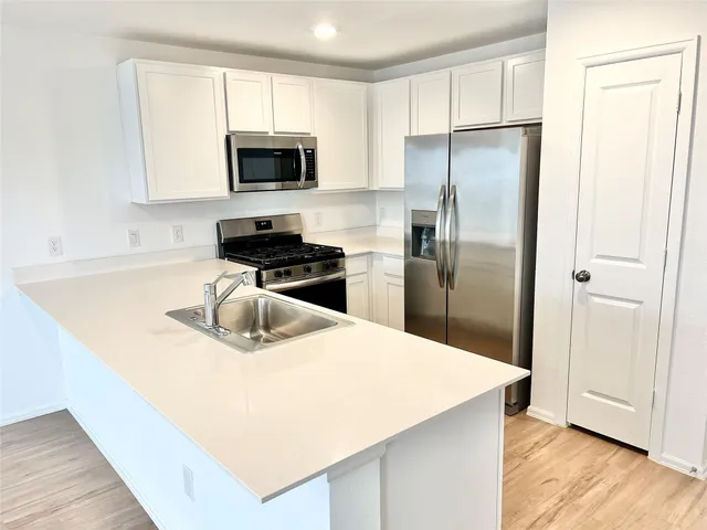 a kitchen with a refrigerator a microwave a sink and cabinets