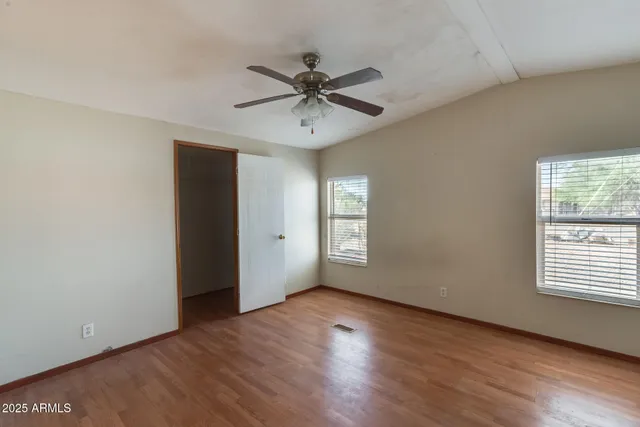 a view of an empty room with wooden floor and a window