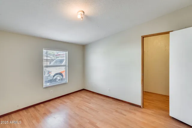 an empty room with wooden floor fan and windows