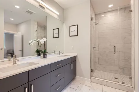 a bathroom with a shower sink vanity and mirror