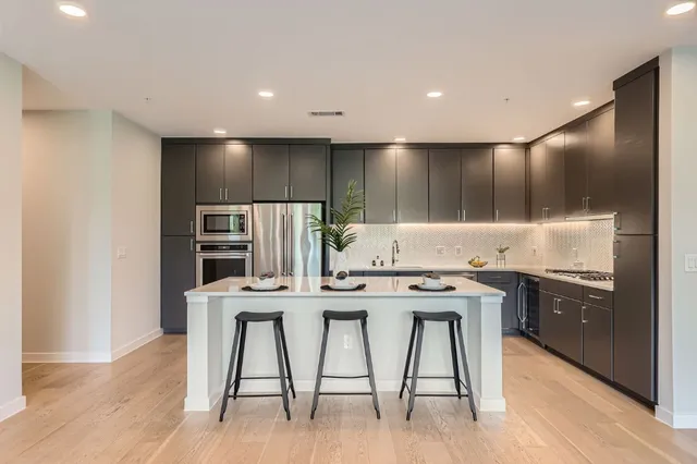 a kitchen with stainless steel appliances kitchen island granite countertop a stove a refrigerator and a refrigerator