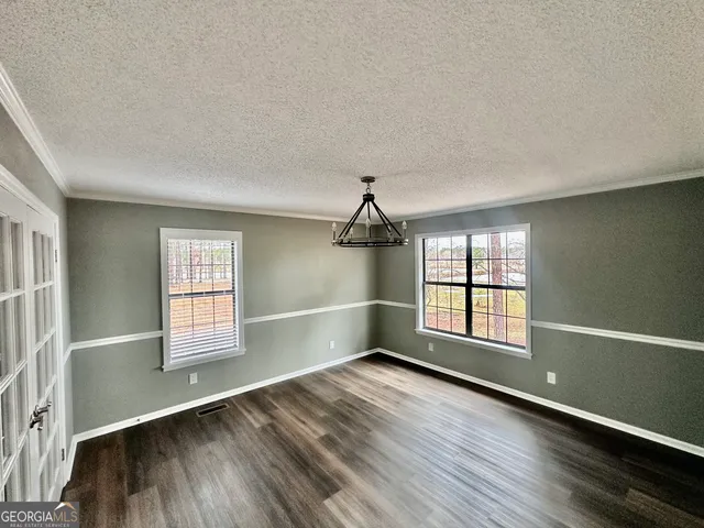 an empty room with wooden floor fireplace and windows