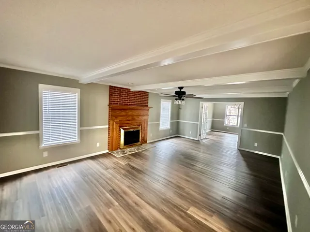 an empty room with wooden floor chandelier and windows