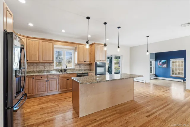 a large kitchen with stainless steel appliances granite countertop a stove and a wooden floors