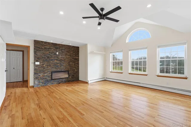 a view of an empty room with wooden floor fireplace and a window