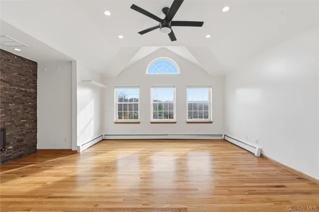 a view of an empty room with window and wooden floor