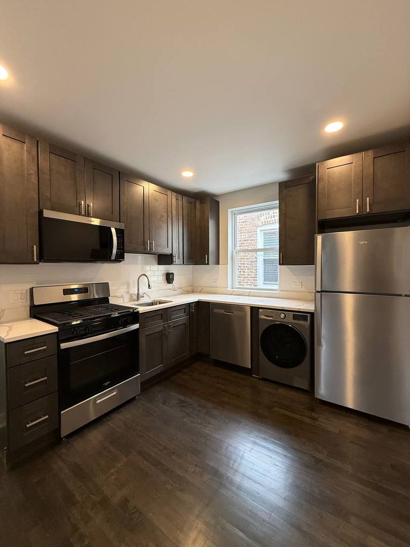 3247 West Thomas Street, Unit 1R Chicago, IL 60651 - Photo 2 of 7 a kitchen with stainless steel appliances wooden cabinets and a refrigerator