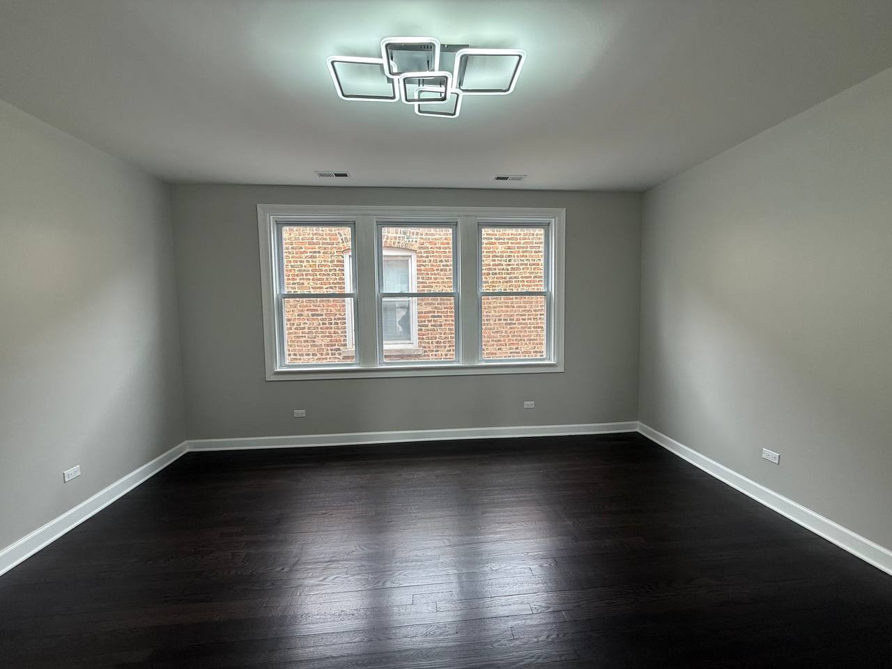 3247 West Thomas Street, Unit 1R Chicago, IL 60651 - Photo 3 of 7 a view of an empty room with wooden floor and a window