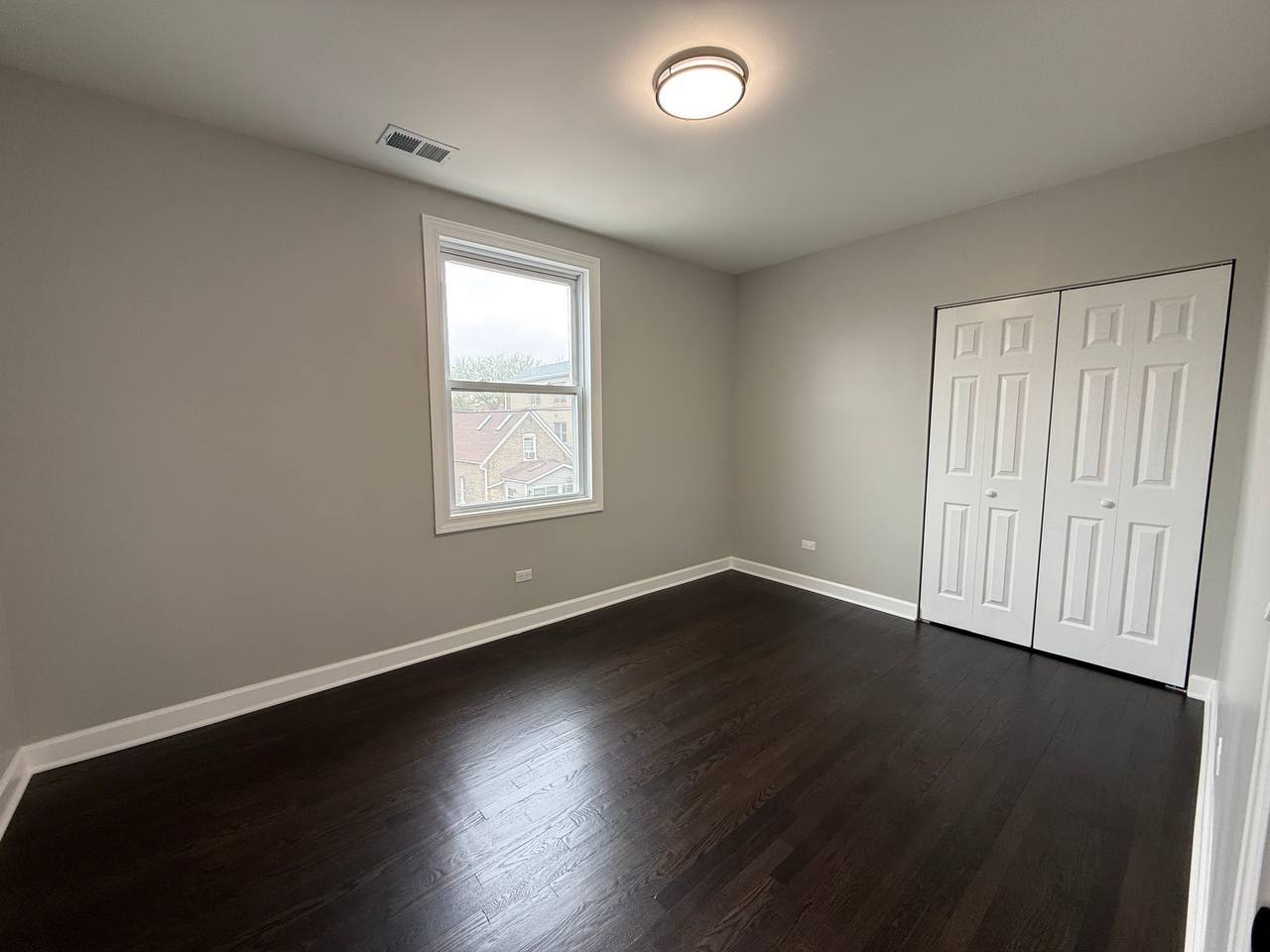 3247 West Thomas Street, Unit 1R Chicago, IL 60651 - Photo 5 of 7 an empty room with wooden floor and windows