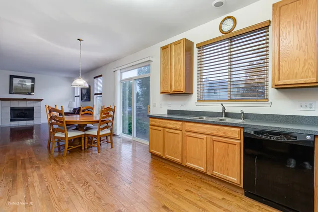 a kitchen with granite countertop a stove a sink dishwasher a dining table and chair with wooden floor