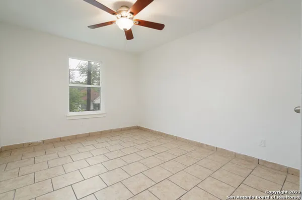 an empty room with windows and fan