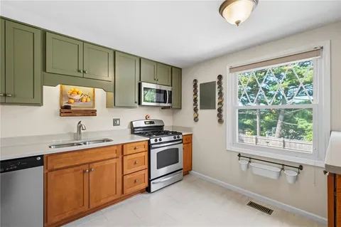 a kitchen with a sink cabinets stainless steel appliances and a large window