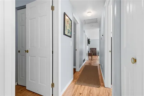 a view of a hallway with wooden floor and a bathroom