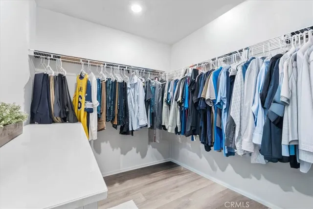 a walk in closet with wooden floor