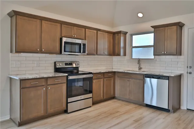 a kitchen with granite countertop wooden cabinets stainless steel appliances and a sink