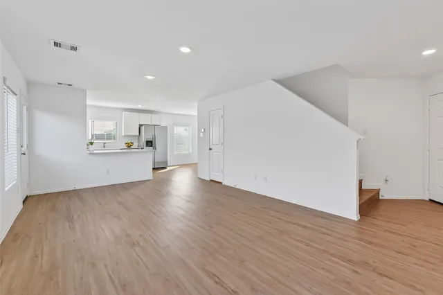 a view of an empty room with wooden floor and windows
