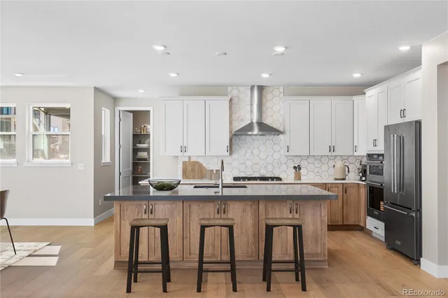 a kitchen with stainless steel appliances granite countertop a table chairs sink refrigerator and cabinets