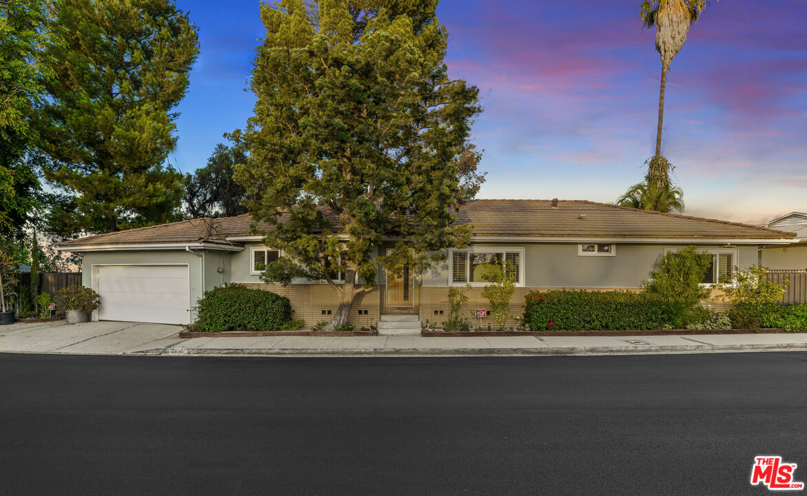 2438 Roscomare Road Los Angeles, CA 90077 - Photo 5 of 17 a front view of a house with a garden and yard