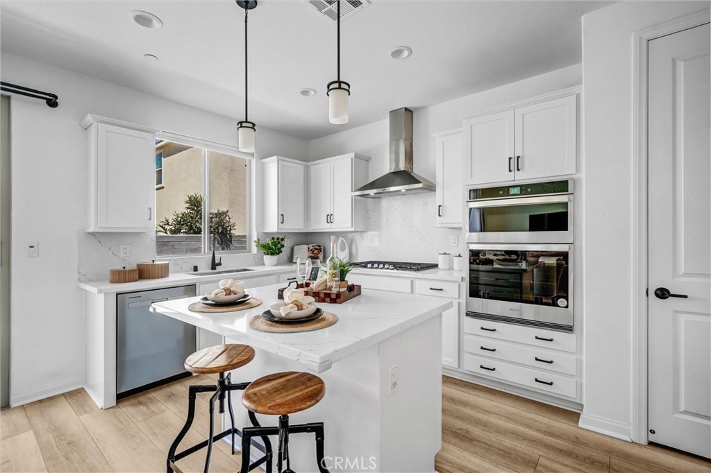 653 Longhorn Way Rancho Mission Viejo, CA 92694 - Photo 11 of 30 a kitchen with stainless steel appliances kitchen island granite countertop a stove a microwave a dining table and chairs with wooden floor