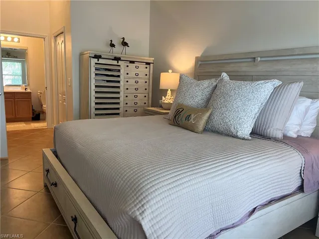 a large bed sitting in a bedroom next to a cabinet and a lamp