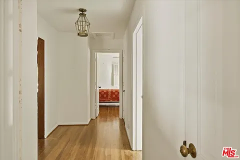 a view of a room that has a bed and wooden floor