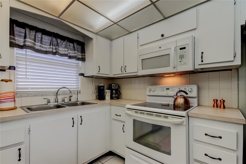 4775 Cove Circle, Unit 1008 St. Petersburg, FL 33708 - Photo 11 of 45 a kitchen with white cabinets and appliances