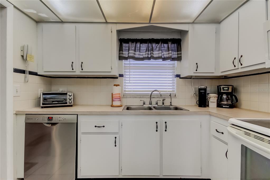 4775 Cove Circle, Unit 1008 St. Petersburg, FL 33708 - Photo 13 of 45 a kitchen with granite countertop a sink a stove and cabinets