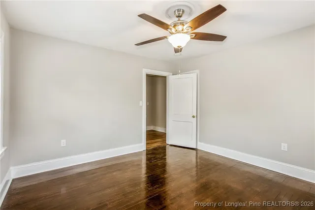 an empty room with wooden floor and ceiling fan