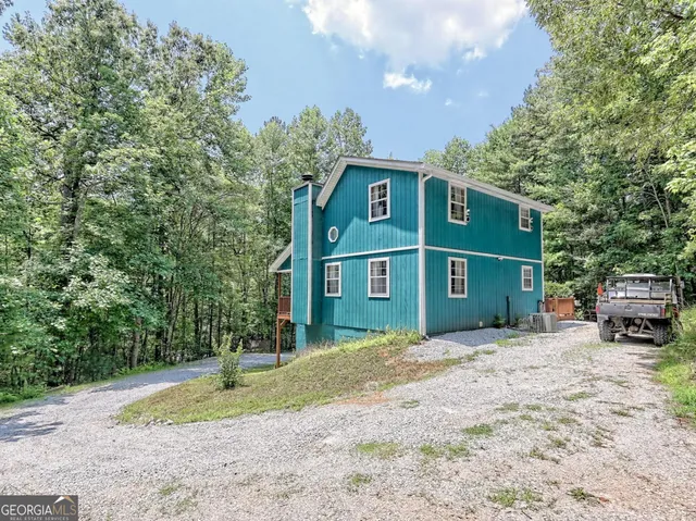 a view of a house with a yard and large trees