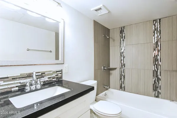 a bathroom with a sink a toilet and shower a mirror