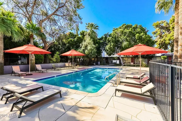 a view of swimming pool with lounge chairs under an umbrella