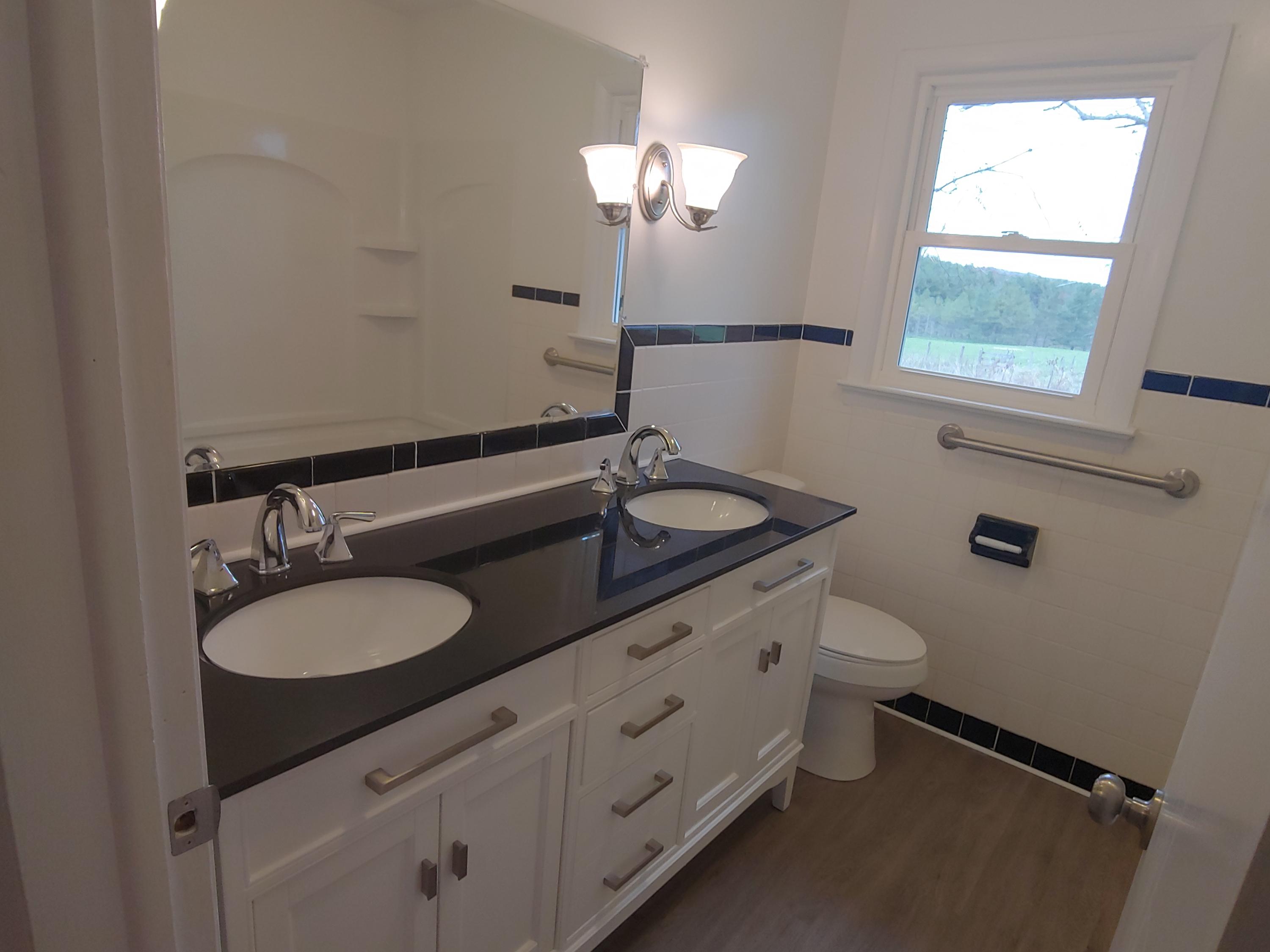 706 Alum Ridge Road Northwest Willis, VA 24380 - Photo 22 of 56 a bathroom with a granite countertop sink a toilet and a mirror